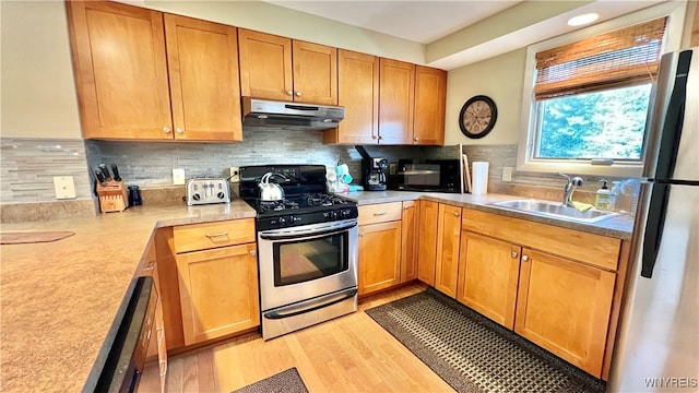 kitchen featuring tasteful backsplash, sink, appliances with stainless steel finishes, and light hardwood / wood-style flooring