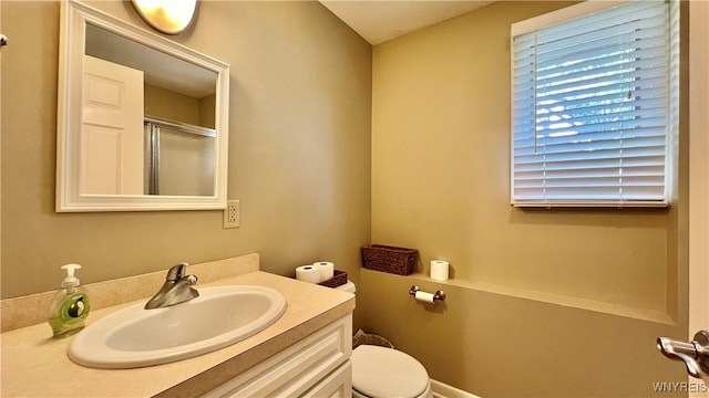 bathroom with vanity, a shower with shower door, and toilet