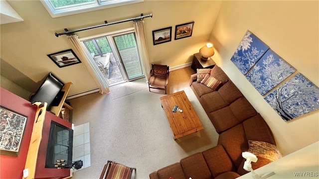 living room featuring a skylight, a towering ceiling, and a baseboard heating unit