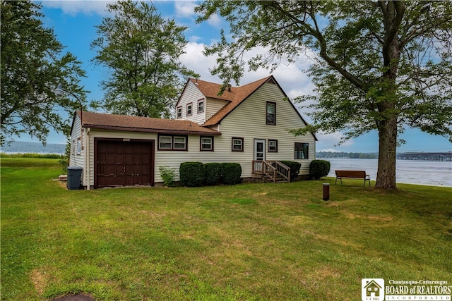 view of front of property with a front yard, a garage, and a water view