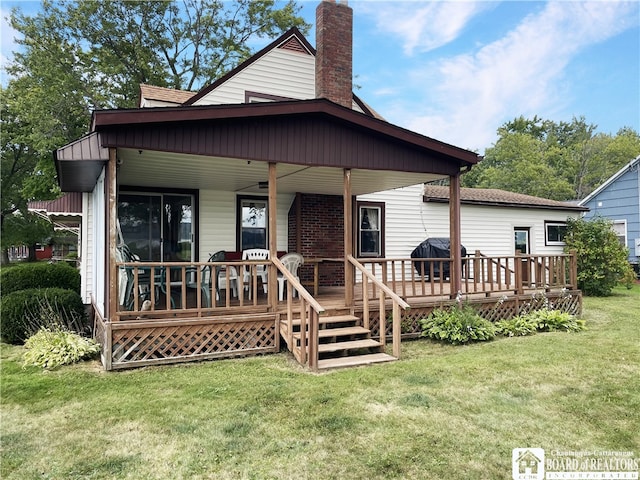 rear view of house featuring a yard and a wooden deck