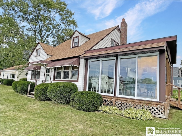 back of property with a yard and a sunroom