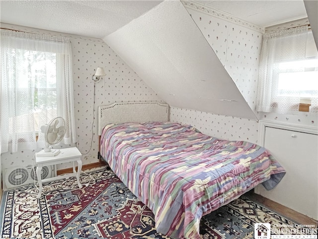 bedroom with multiple windows, a textured ceiling, and vaulted ceiling