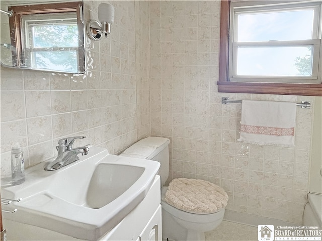 bathroom featuring vanity, toilet, and tile walls