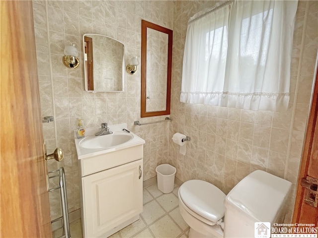 bathroom with tile walls, vanity, toilet, and tile patterned floors