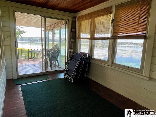 unfurnished sunroom featuring wood ceiling, a water view, and plenty of natural light