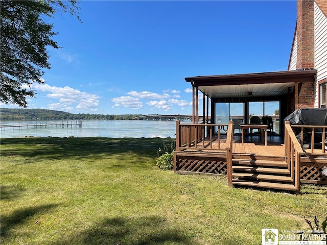 exterior space with a deck with water view and a lawn