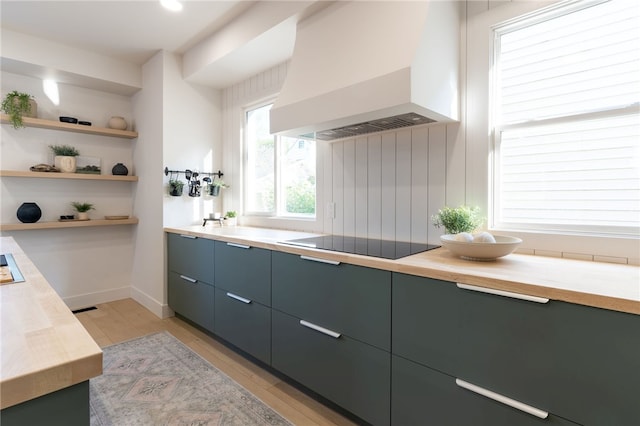 kitchen with light hardwood / wood-style floors, custom range hood, black electric stovetop, and wood counters