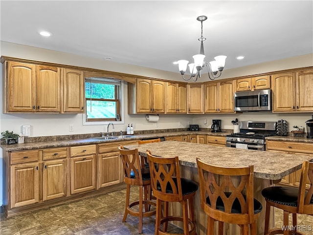 kitchen featuring a center island, an inviting chandelier, appliances with stainless steel finishes, sink, and a kitchen breakfast bar