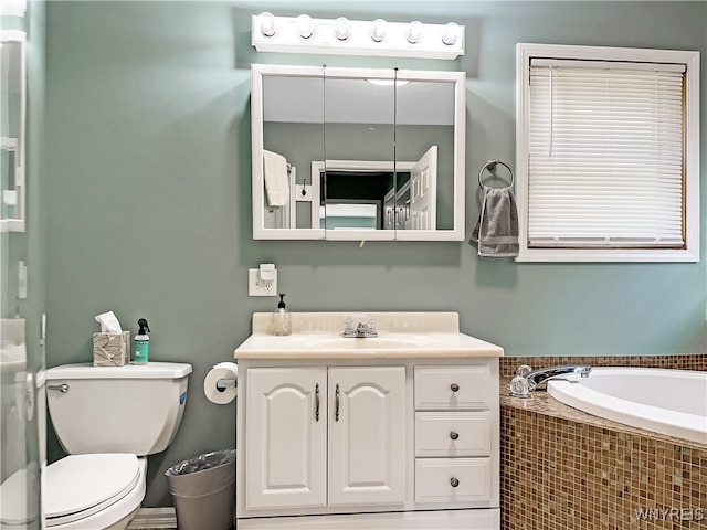 bathroom with vanity, toilet, and a relaxing tiled tub