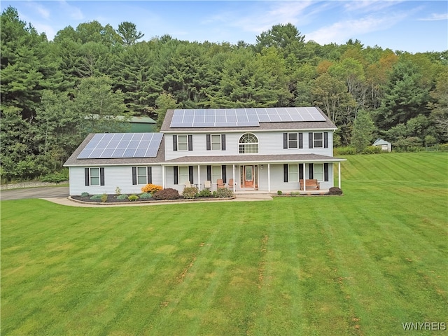 colonial-style house featuring a front yard, covered porch, and solar panels