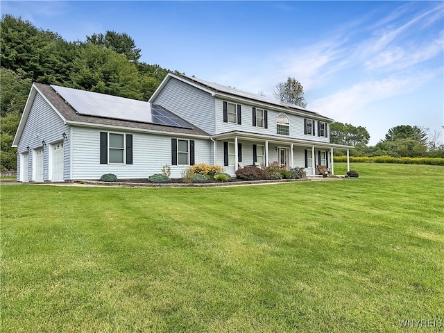 view of front of property featuring a garage, covered porch, solar panels, and a front yard