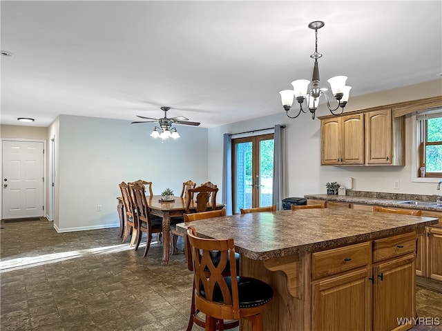 kitchen featuring pendant lighting, a center island, a healthy amount of sunlight, and ceiling fan with notable chandelier