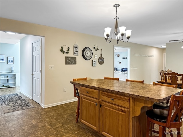 kitchen with ceiling fan with notable chandelier, a kitchen island, hanging light fixtures, and a breakfast bar