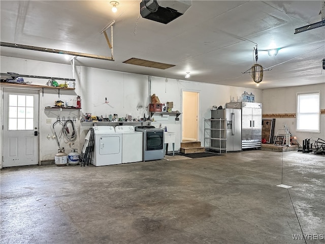 garage featuring stainless steel fridge, washer and clothes dryer, and a garage door opener