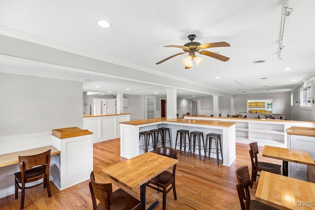 dining area featuring crown molding, ceiling fan, light wood-type flooring, and track lighting