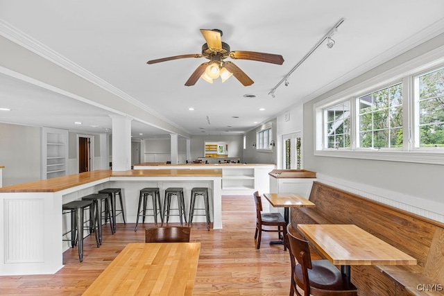 dining room featuring rail lighting, ceiling fan, ornamental molding, and light hardwood / wood-style flooring