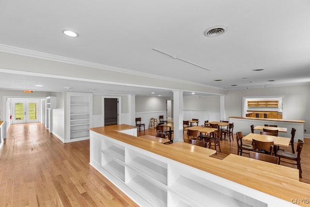 interior space featuring crown molding, wood counters, french doors, and light hardwood / wood-style floors