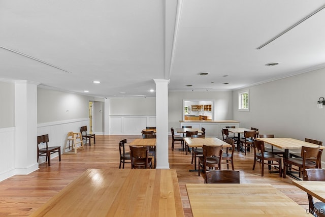 interior space featuring light hardwood / wood-style flooring, ornamental molding, and ornate columns