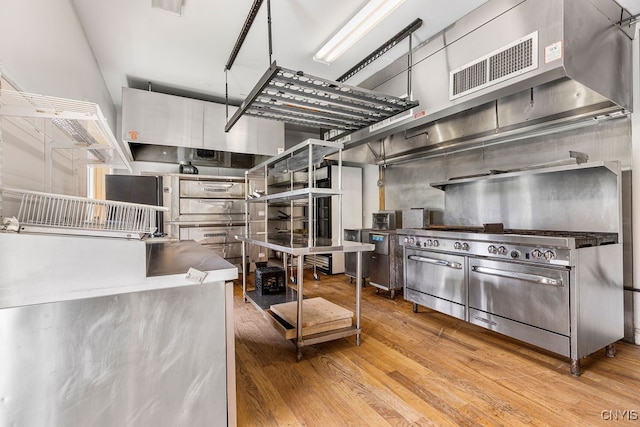 kitchen featuring a high ceiling, white cabinets, and light hardwood / wood-style floors