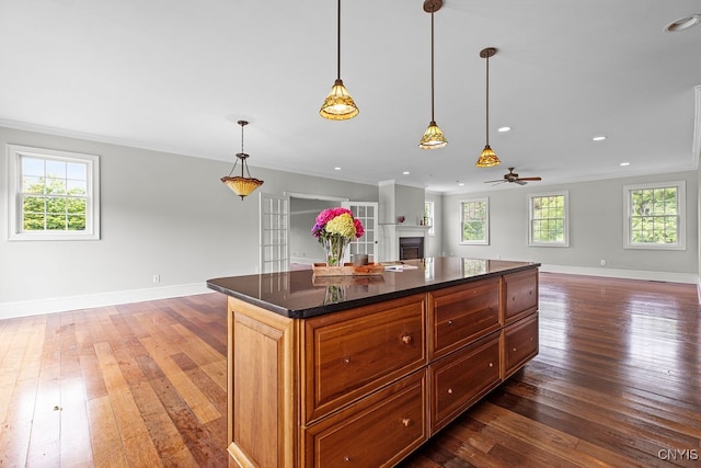 kitchen with a wealth of natural light, a center island, ceiling fan, and dark hardwood / wood-style floors