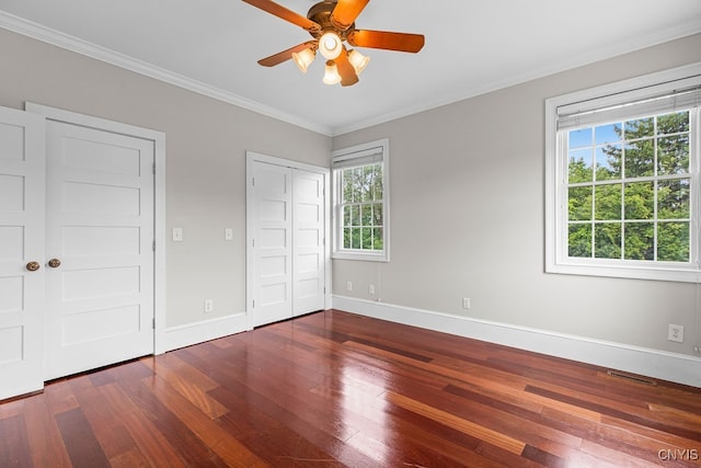 unfurnished bedroom featuring crown molding, dark hardwood / wood-style flooring, ceiling fan, and multiple windows