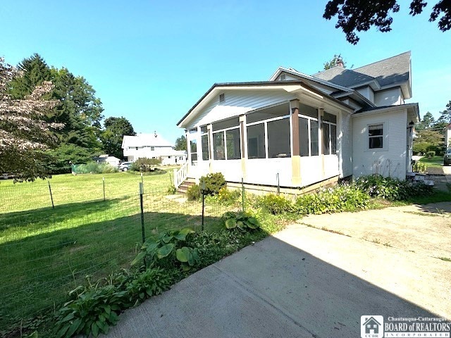 view of property exterior featuring a lawn and a sunroom