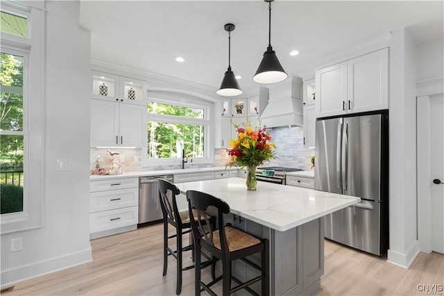 kitchen with a center island, custom range hood, appliances with stainless steel finishes, and white cabinets