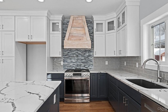 kitchen featuring stainless steel appliances, sink, premium range hood, and white cabinetry