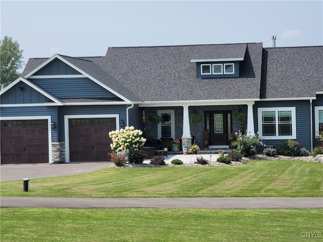 craftsman-style home featuring a garage, covered porch, and a front lawn