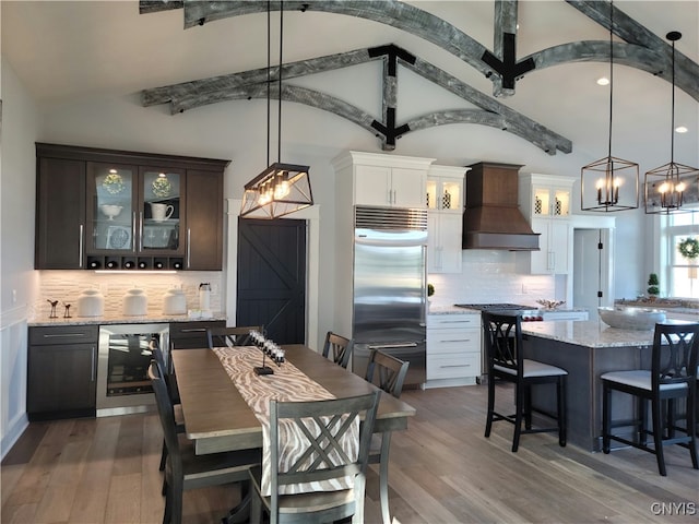 dining area featuring beverage cooler, hardwood / wood-style flooring, a chandelier, and vaulted ceiling with beams