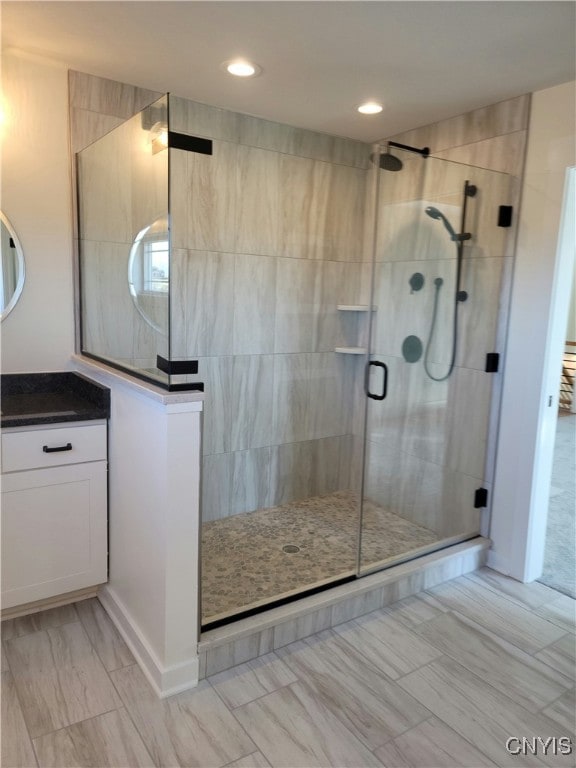 bathroom with a shower with door and vanity