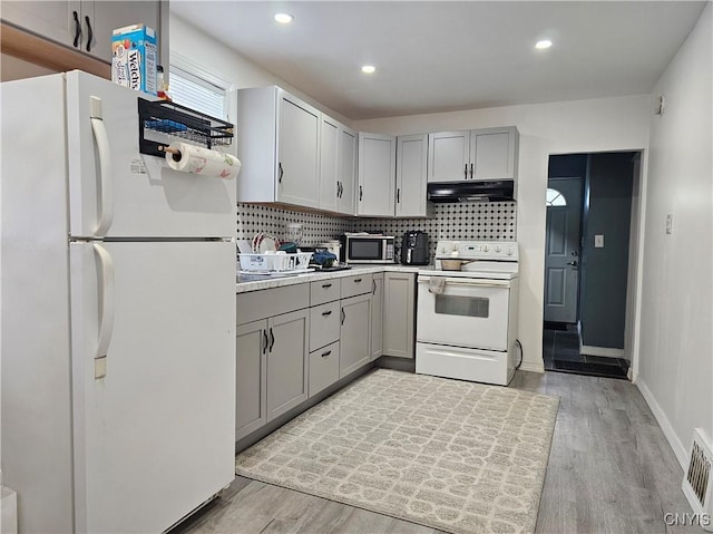 750 Lansing St, Utica, NY 13501 - kitchen featuring gray cabinetry, white appliances, decorative backsplash, and exhaust hood