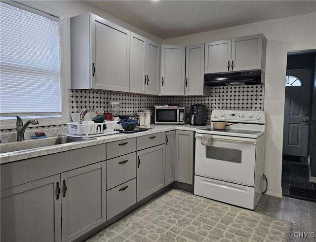 750 Lansing St, Utica, NY 13501 - kitchen featuring under cabinet range hood, stainless steel microwave, gray cabinetry, and electric stove