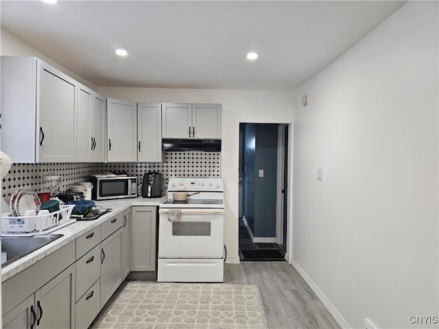 750 Lansing St, Utica, NY 13501 - kitchen with range hood, stainless steel microwave, light countertops, light wood-type flooring, and electric range
