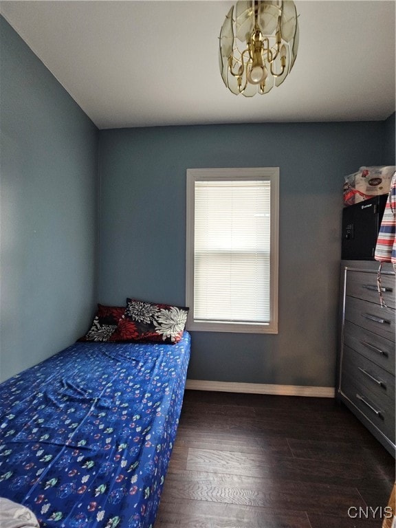 bedroom with dark wood-type flooring and an inviting chandelier