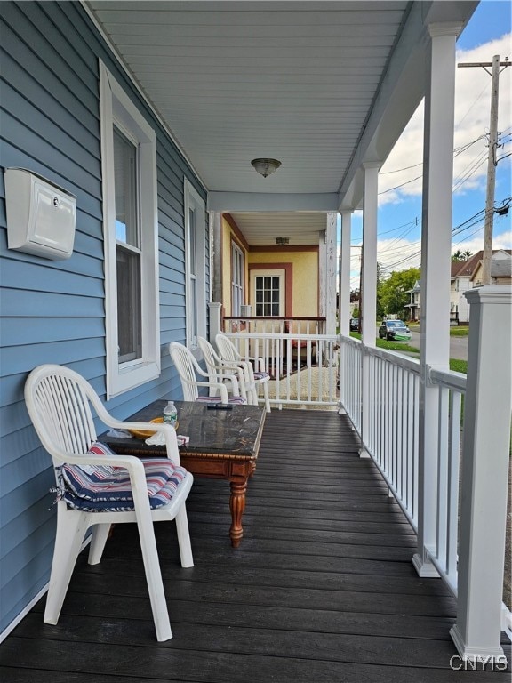 wooden terrace with covered porch and a wall mounted air conditioner