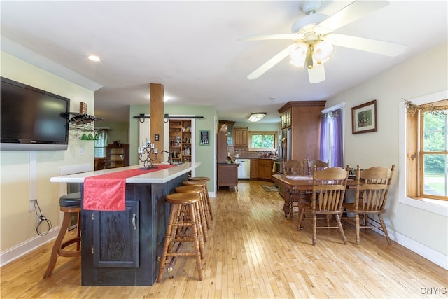 dining space with light hardwood / wood-style flooring, indoor bar, and ceiling fan