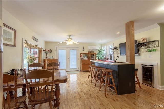 dining room featuring a wall unit AC, wine cooler, ceiling fan, french doors, and light hardwood / wood-style floors