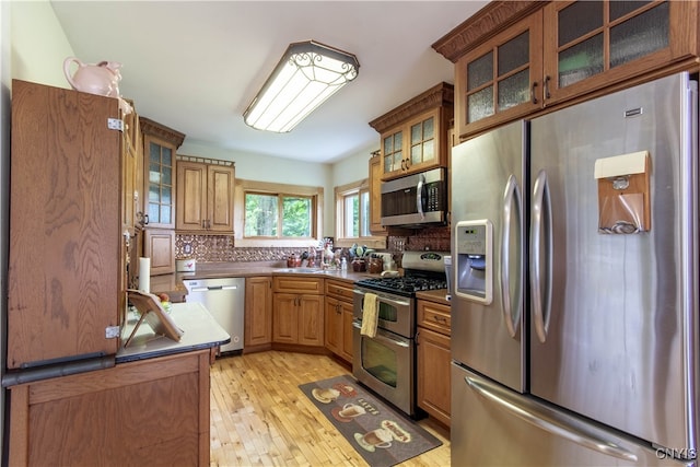 kitchen featuring light wood-type flooring, appliances with stainless steel finishes, sink, and decorative backsplash