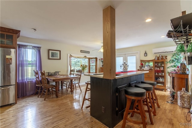 kitchen featuring a wealth of natural light, stainless steel refrigerator, a kitchen breakfast bar, and light hardwood / wood-style floors