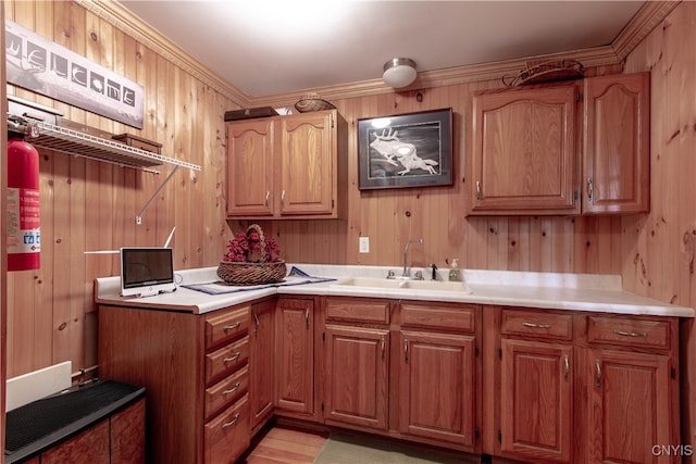 kitchen with light hardwood / wood-style flooring, wood walls, ornamental molding, and sink