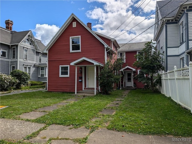 view of front of property featuring a front lawn, a chimney, and fence