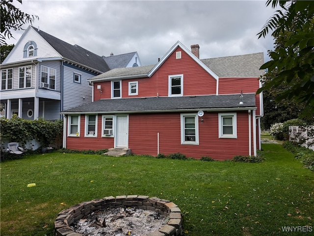 back of property with a lawn and a fire pit