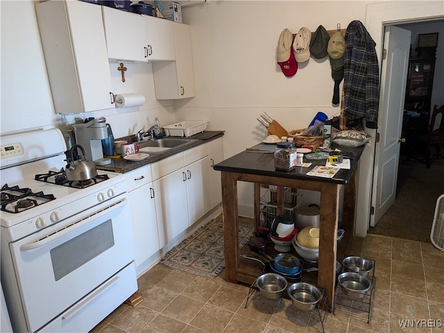 kitchen with gas range gas stove, white cabinetry, and sink