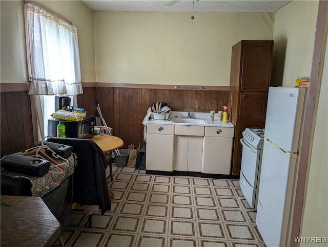 kitchen featuring white appliances, wood walls, ceiling fan, and a textured ceiling