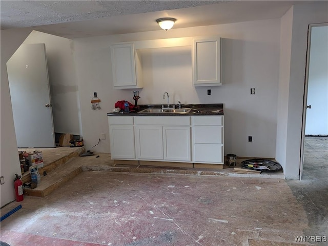 kitchen with dark countertops, a sink, and white cabinets