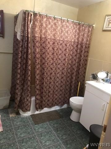 bathroom with shower / bath combo, tile patterned flooring, and toilet