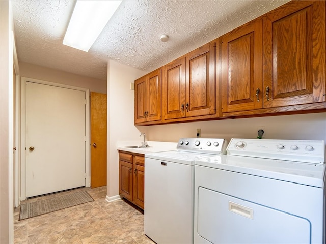 laundry room with a textured ceiling, cabinets, washer and clothes dryer, and sink