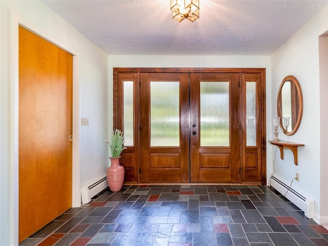 foyer entrance with french doors, a textured ceiling, and baseboard heating